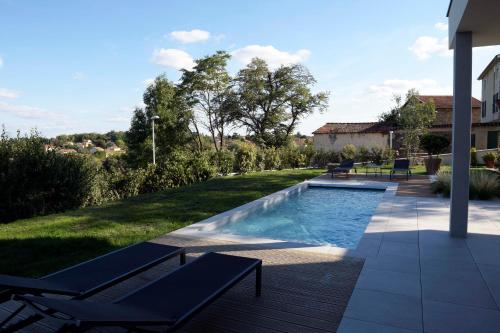 einen Pool in einem Garten mit Stühlen und einem Haus in der Unterkunft Maison Canopée in Saint-Genis-les-Ollières