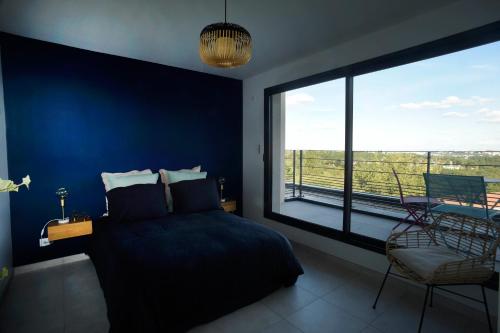 een blauwe slaapkamer met een bed en een groot raam bij Maison Canopée in Saint-Genis-les-Ollières