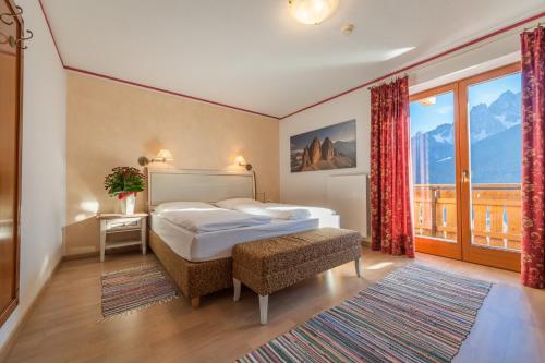 a bedroom with a bed and a large window at Hotel Schopfenhof in San Candido