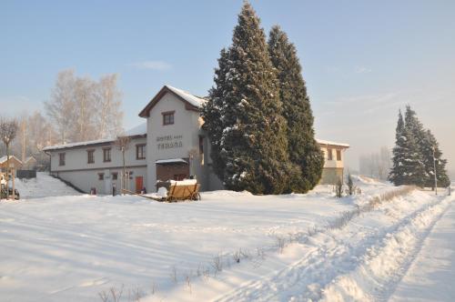 a snow covered yard with a building and trees at Hotel Terasa in Frýdek-Místek