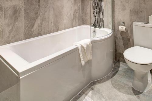 a bathroom with a white tub and a toilet at Lord Haldon Country Hotel, Sure Hotel Collection by Best Western in Exeter