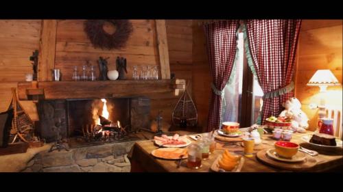 a living room with a fireplace and a table with food at Chalet-Hôtel Les Cimes in Le Grand-Bornand