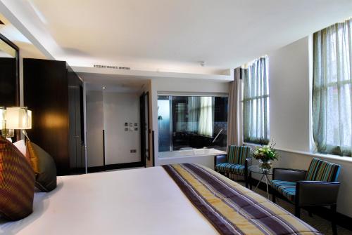 a hotel room with a bed and two chairs at The Montcalm At Brewery London City in London