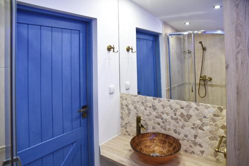 シュチェチンにあるIn the Attic Apartmentsの青いドアとシンク付きのバスルーム