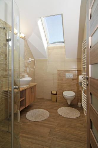 a bathroom with a toilet and a sink and a skylight at Hotel Corso in Siófok