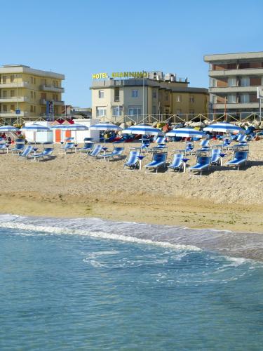 a group of chairs and umbrellas on a beach at Hotel Giannino in Porto Recanati