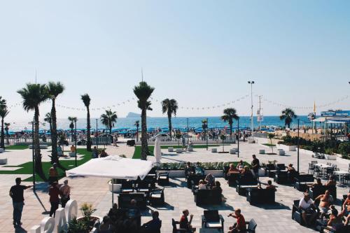 a group of people sitting in a patio near the beach at Apartamentos Oasis Benidorm in Benidorm