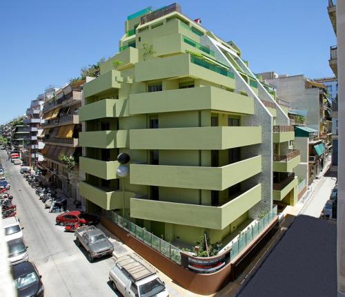 a tall green building with cars parked in a parking lot at Athens Mosaico Suites & Apartments in Athens