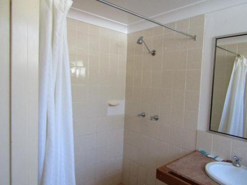 a bathroom with a shower, sink, and tub at Beach Drive Motel in Batemans Bay