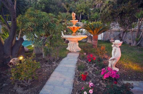 a fountain in the middle of a garden with flowers at Hotel Riva del Sole in Ischia