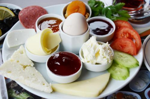 Un plato de comida con huevos, mermelada y queso. en Rose Garden Apart Hotel, en Alanya