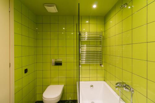 a green tiled bathroom with a toilet and a tub at Athens Mosaico Suites & Apartments in Athens