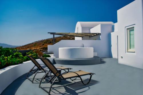 two chairs and a table on a balcony at Amber Light Villas in Imerovigli