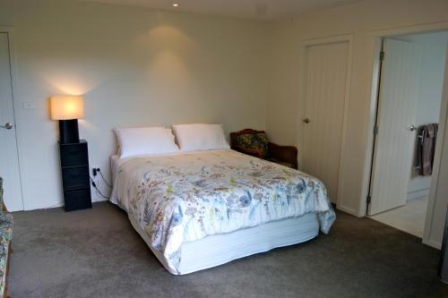 a bedroom with a bed and a lamp in it at Waihi Beach Getaway-Studio, Ensuite & Private Deck in Waihi Beach