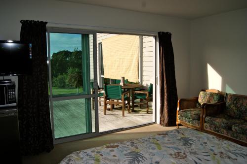 a bedroom with a bed and a balcony with a table and chairs at Waihi Beach Getaway-Studio, Ensuite & Private Deck in Waihi Beach