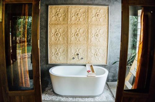 a bath tub in a room with a wall at Surf N Sun - Arugam Bay in Arugam Bay