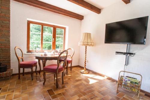 a dining room with a table and chairs and a flat screen tv at Landsitz Braderup Festland in Braderup