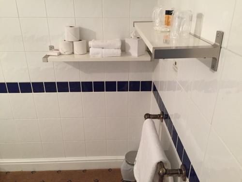 a bathroom with blue and white tiles and towels at The Tudor Hotel in Harrow