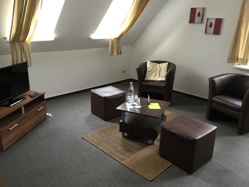 ein Wohnzimmer mit Stühlen, einem TV und einem Tisch in der Unterkunft Pension Zum Angestellten in Porta Westfalica