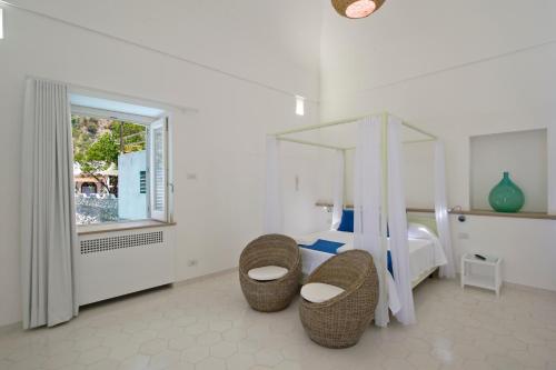 a bedroom with a bed and two chairs and a window at Villa Imperati in Praiano