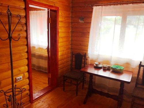 um quarto com uma mesa e uma janela num chalé de madeira em Guest House U Stasuka em Vorokhta