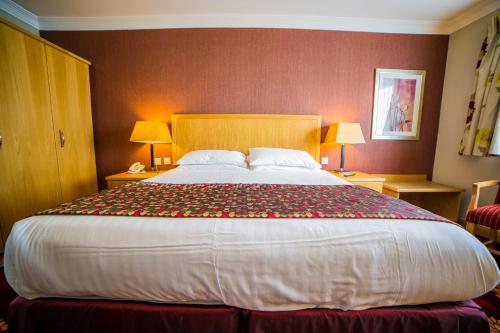 a large bed in a hotel room with two lamps at Curran Court Hotel in Larne