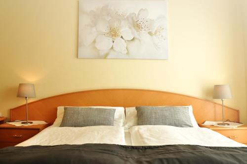 a bedroom with a bed with two lamps and a painting at Gästehaus Hofer in Gumpoldskirchen