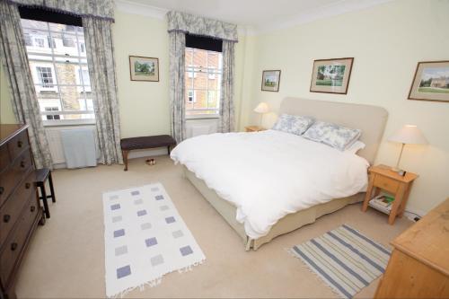una camera con un letto bianco e due finestre di JOIVY Luxurious 2BR flat in Pimlico, near Warwick sq a Londra