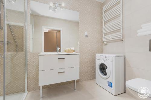 a bathroom with a washing machine and a washer at Grace Apartment I in Kołobrzeg