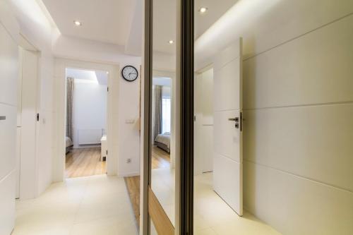 un couloir avec des portes coulissantes en verre et une horloge sur le mur dans l'établissement Apartament PAJO I -Rezydencja Tatry--GROTA SOLNA--TARAS--GARAŻ PODZIEMNY, à Zakopane