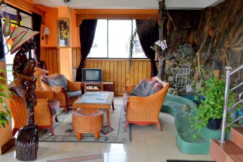 a living room with chairs and a table and a tv at Highcliffe Guest House in Haputale