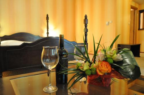 a table with a glass of wine and a vase of flowers at Hotel Izvora in Arbanasi