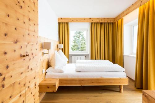 a bedroom with a bed and a wooden wall at Hotel Kreuzberg Monte Croce in Sesto