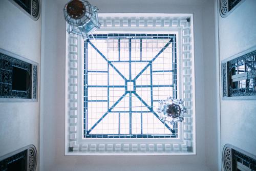 ein Fenster in einem weißen Zimmer mit Blumen darauf in der Unterkunft Riad Anata in Fès
