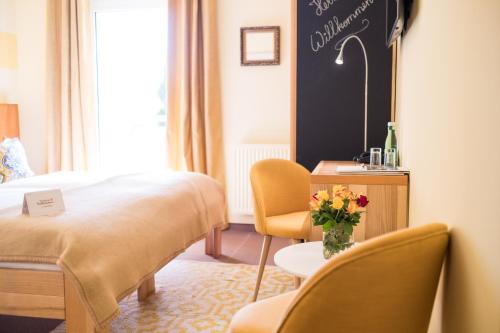 a hotel room with a bed and chairs and a table with flowers at Das Eisenberg in Sankt Martin an der Raab
