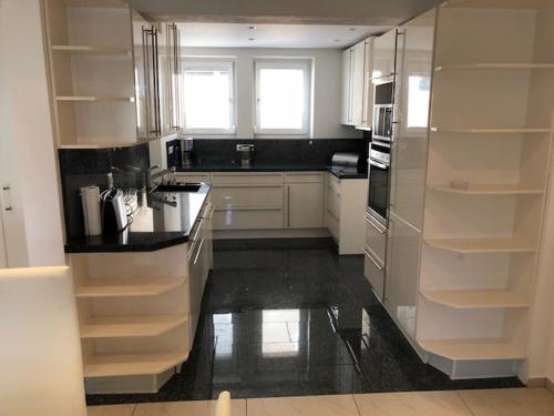 a kitchen with white cabinets and a black floor at Ferienwohnung Amperblick Fürstenfeldbruck in Fürstenfeldbruck