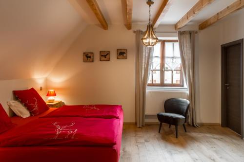 een slaapkamer met een rood bed en een stoel bij Les Chambres Chez Christine in Ottrott