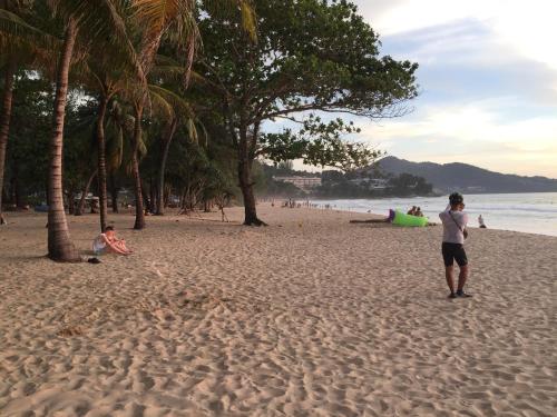 a man standing on a beach with palm trees at Surin Sunset Hotel - SHA in Surin Beach