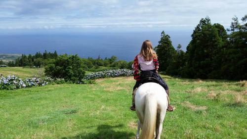 a woman riding a white horse in a field at Pátio Ecolodge in Cedros