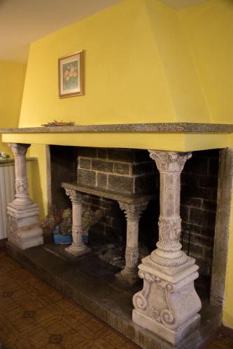 a stone fireplace in a room with a yellow wall at Il Camino in Anzino