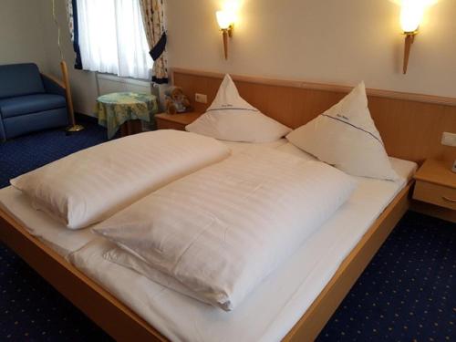 un grande letto con lenzuola e cuscini bianchi di Gasthof Pension Walther a Weißdorf