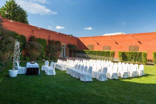 a row of white chairs and tables on the grass at Hotel Guadalajara & Conference Center Affiliated by Meliá in Guadalajara