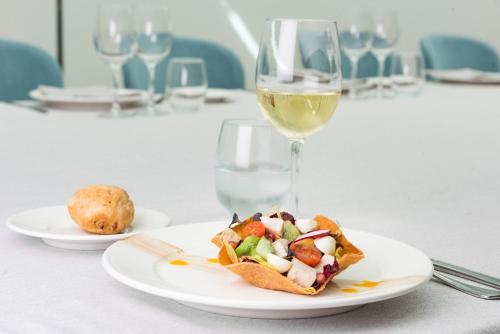 a table with a plate of food and a glass of wine at Hotel Guadalajara & Conference Center Affiliated by Meliá in Guadalajara