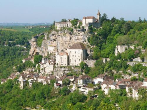 a town on top of a mountain with a church at Hôtel Le Troubadour à Rocamadour in Rocamadour