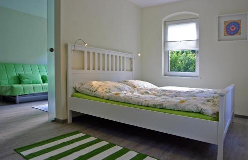 a bedroom with a white bed and a window at Kleines Häuschen - Ferien in Cossebaude in Dresden
