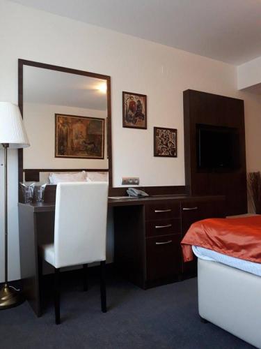 a bedroom with a desk and a bed and a mirror at Семеен хотел Анна-Кристина in Vidin