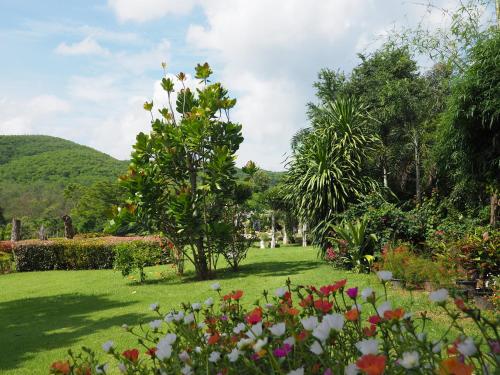 a garden with a tree and flowers in the grass at Baan Ing Khao in Pak Chong