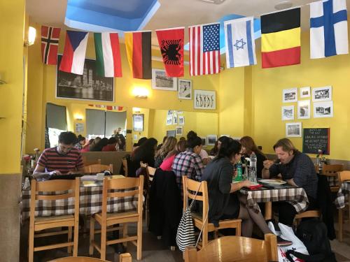 a group of people sitting at tables in a restaurant with flags at Stephen Center B&B in Tirana