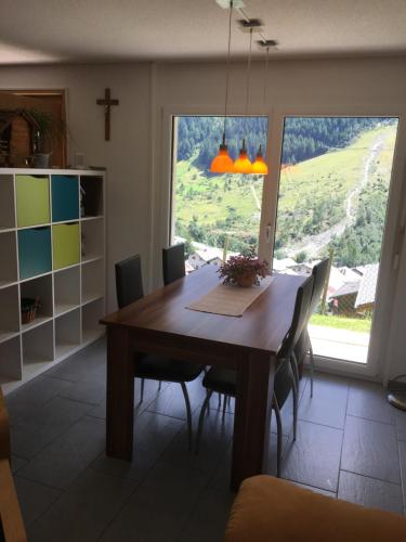 a dining room table with chairs and a large window at Haus Melodie in Wiler