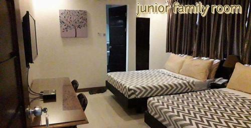 a hotel room with two beds and a table and a desk at Urbantel Hotel in Lucena